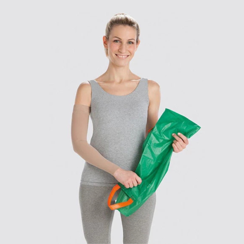 woman in front of grey bakground holding green compression donning aid 